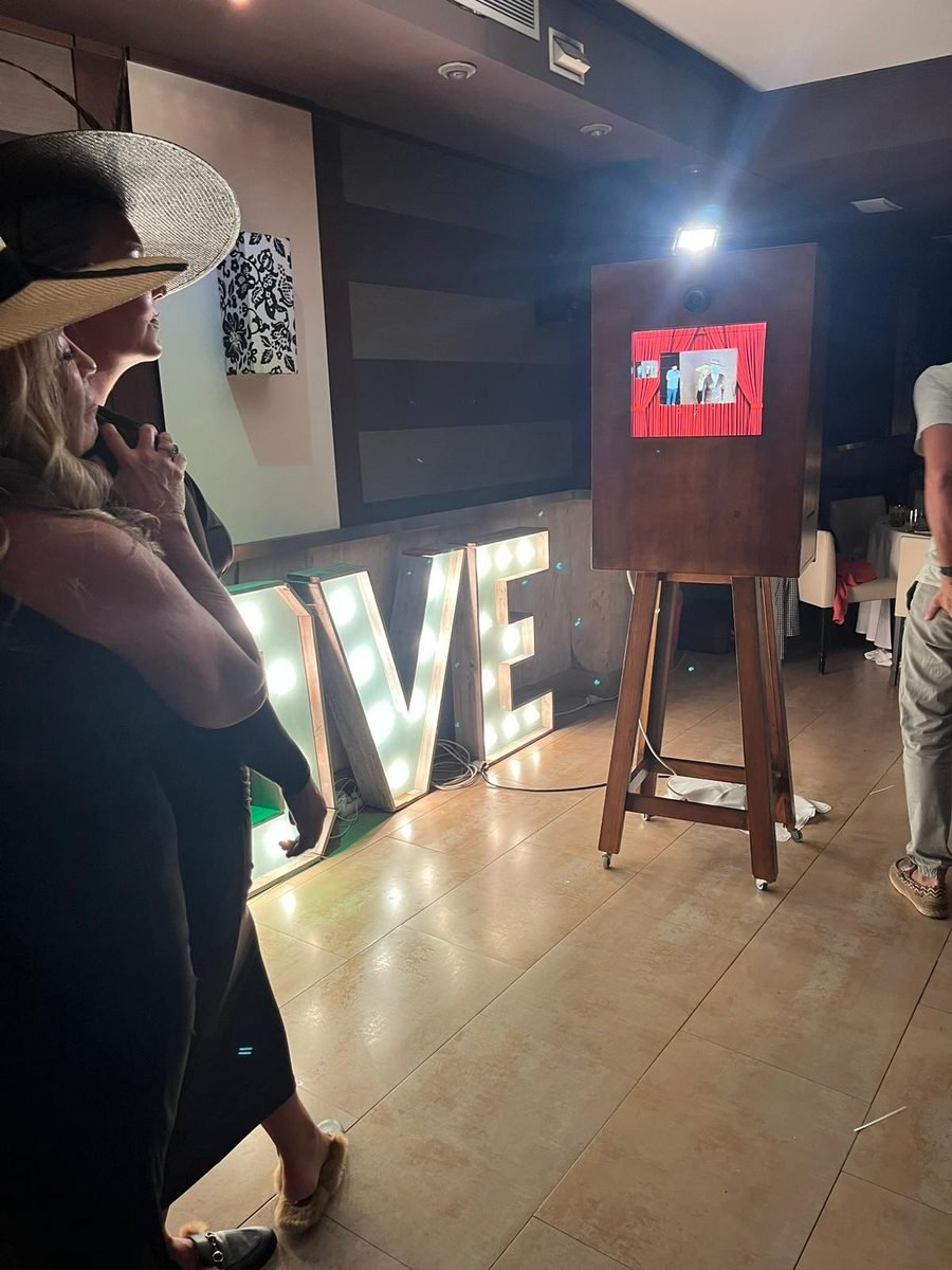 Invitada usando fotomatón retro de madera en celebración de boda